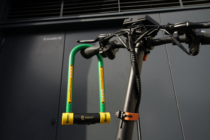 Antivol U CactUs Lock fixé au guidon d'une trotinnette, conçu pour protéger contre les tentatives de vol en milieu urbain.