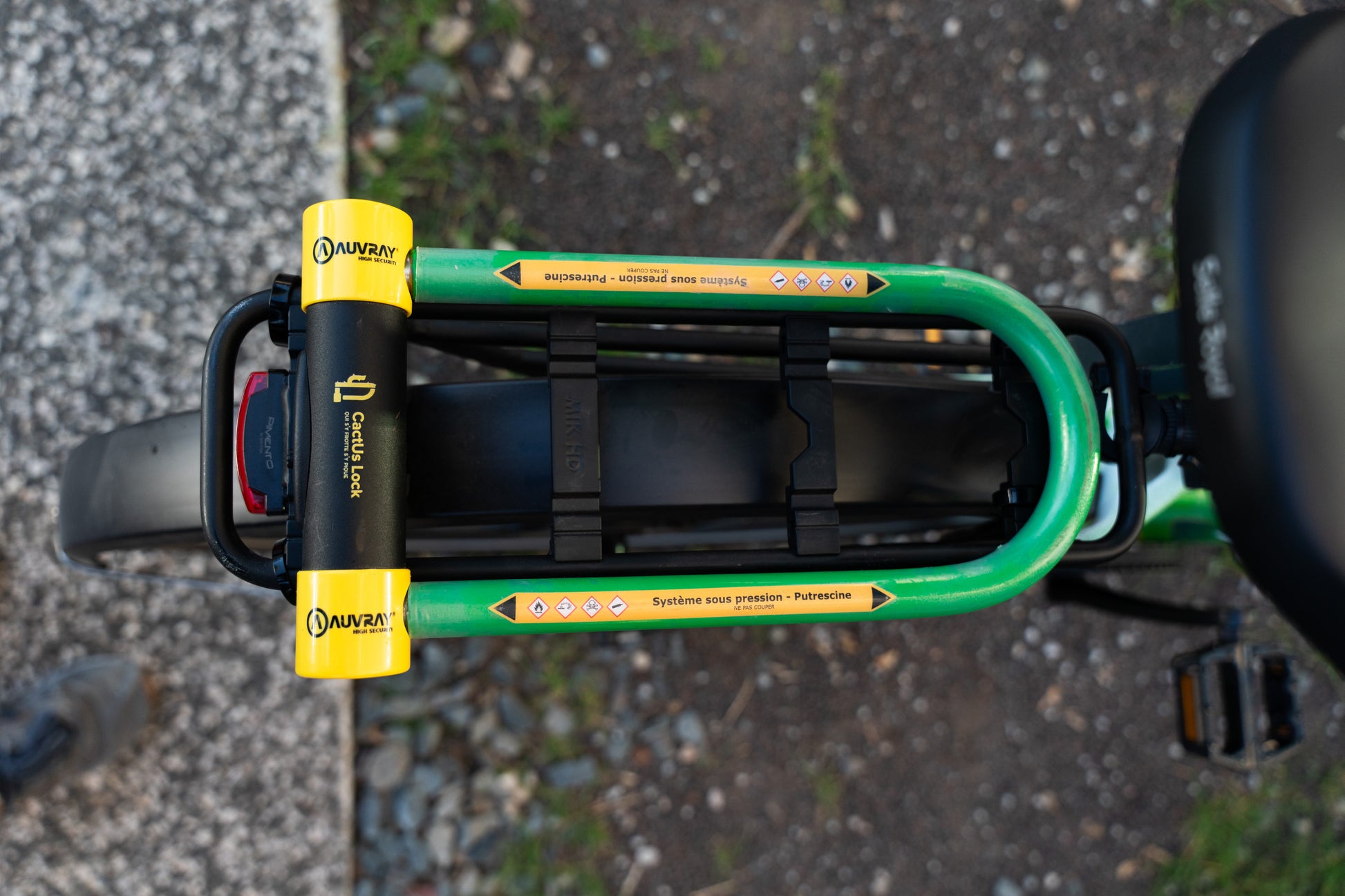 Vue de dessus de l’antivol Le Pionnier de CactUs Lock installé sur le porte-bagages d’un vélo avec signalétique de dissuasion visible.